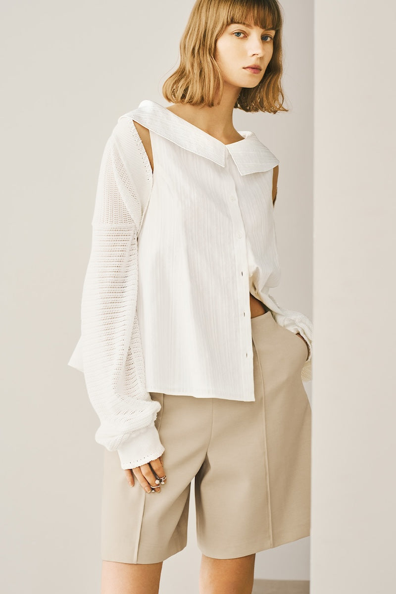 A model is wearing a white shirt and tan shorts.
